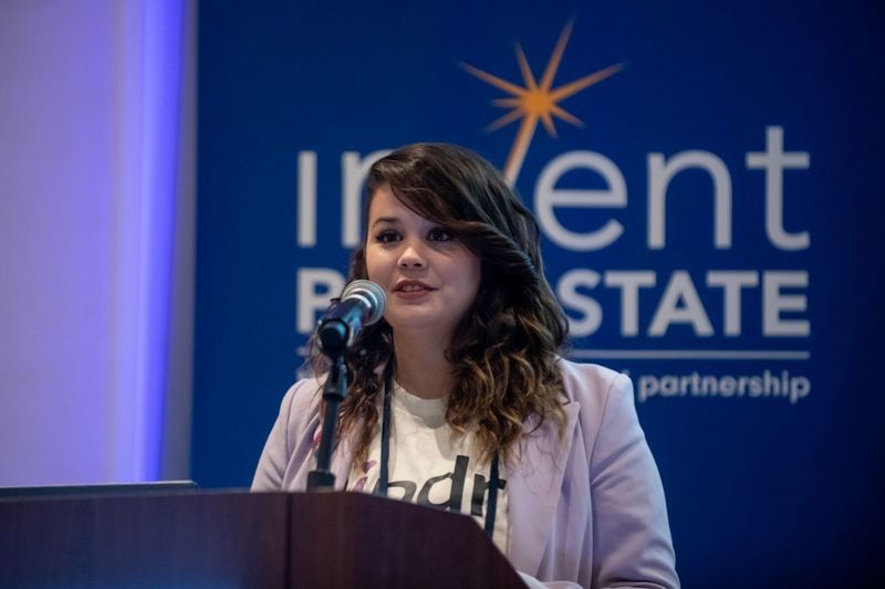 Mary Richardson speaks at podium in front of Invent Penn State signage during the Student Startup Showcase at the Invent Penn State Venture & IP Conference.