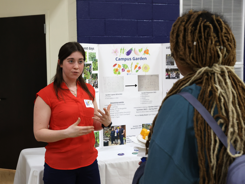 Student explaining campus garden poster to student