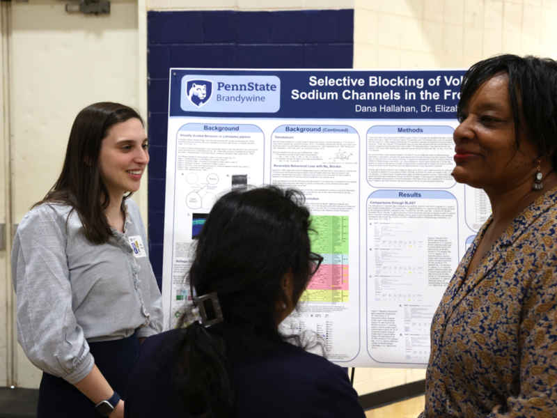 Student explaining research to two guests