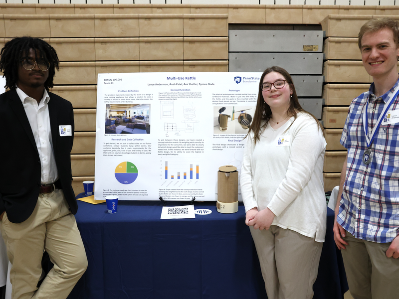 Three students presenting research on a poster