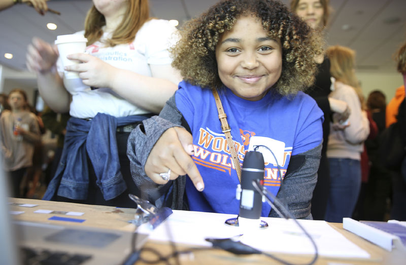 A girl points to a microscope slide.