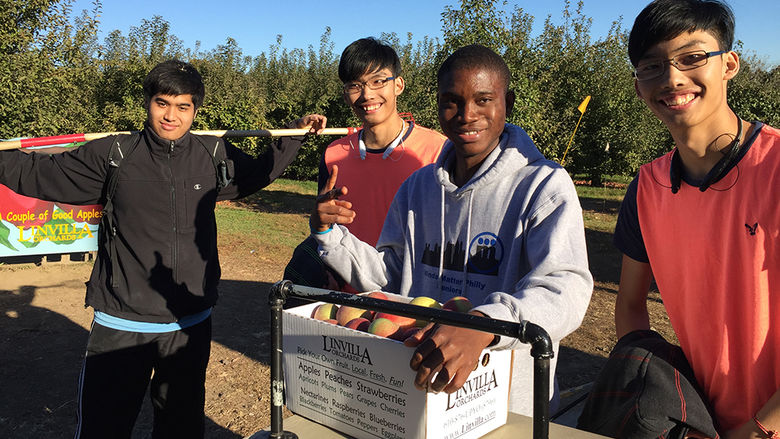 4 male students with box of apples