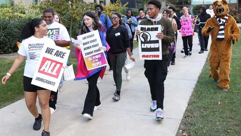 Students walk on campus carrying signs that support diversity, equity and inclusion.