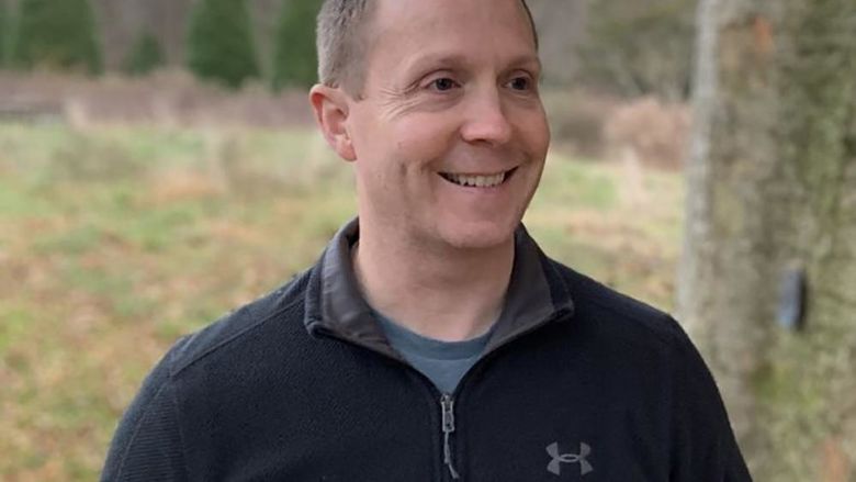 Daniel Hamilton stands outside with trees in the background