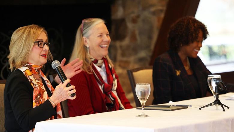 Three women sit at a table facing the audience.