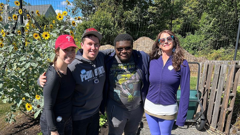 Students and garden manager standing in front of sun flowers