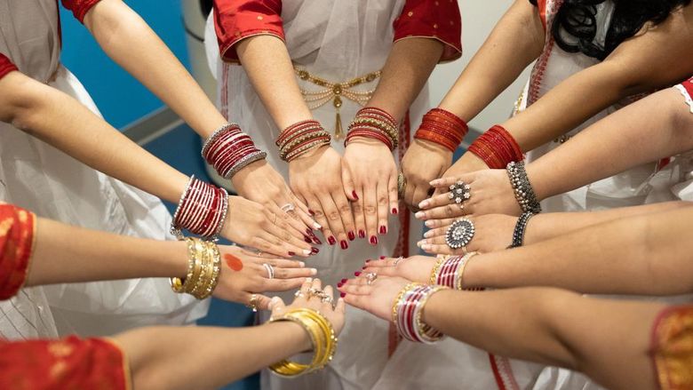 Students show their arms wearing many colorful bracelets and rings.