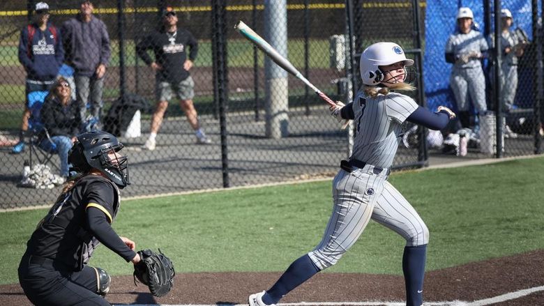 A female softball player swings the bat.