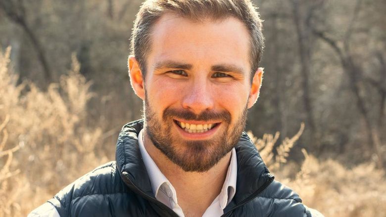 A head shot of a man standing outdoors.