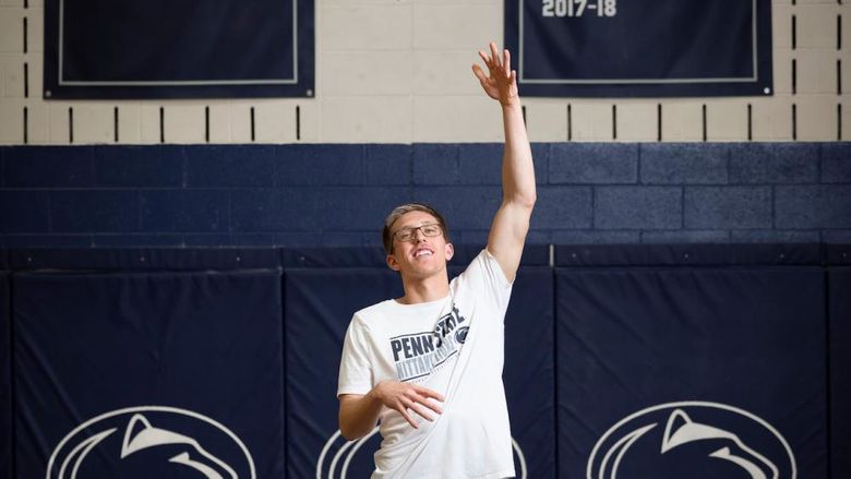 Man with arm up throwing basketball into net