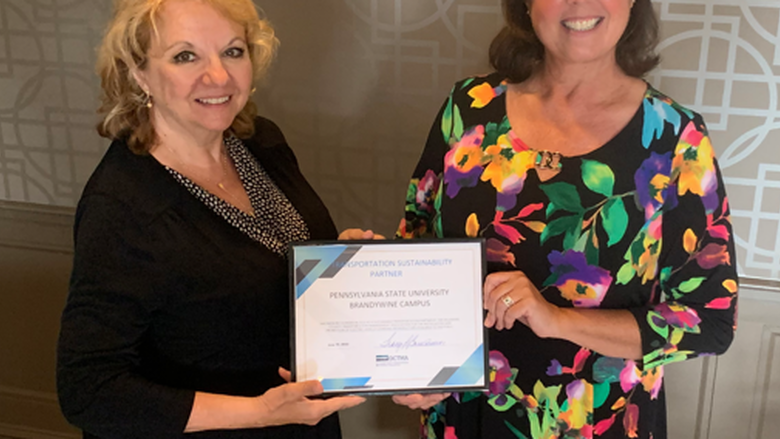 Two women hold up certificate at ceremony