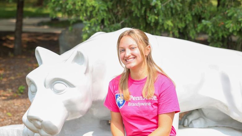 lady in pink shirt sitting next to lion shrine