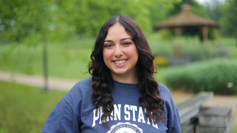 woman wearing blue Penn State sweatshirt leaning on a bridge