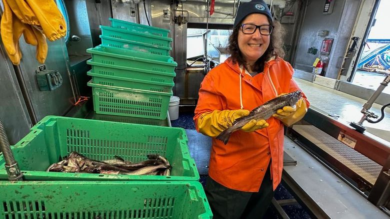 A woman on board a ship hold a fish.