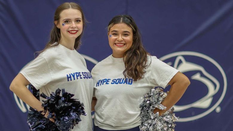 Two female students on the Hype Squad stand in the campus gym.