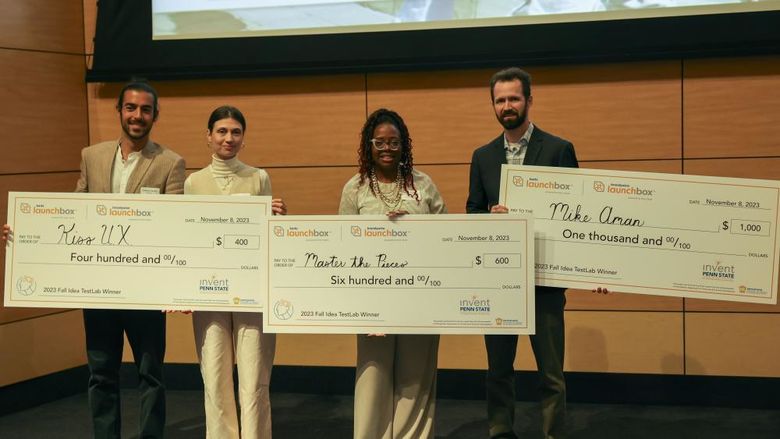 winners of idea TestLab competition standing on stage with large checks for $400, $600 and $1000