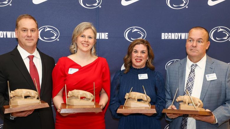 four people holding awards