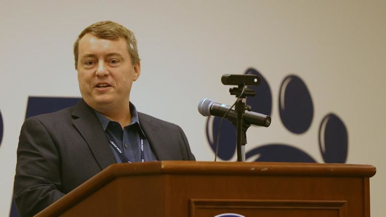 A male professor speaks at a lectern