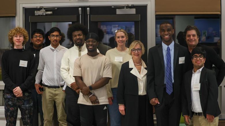 students posing for photo with administrators and coaches