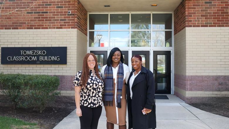 alumnae standing in front of Tomezsko Classroom Building