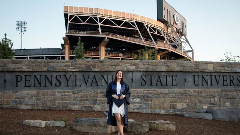 person in cap and gown in front of sports stadium