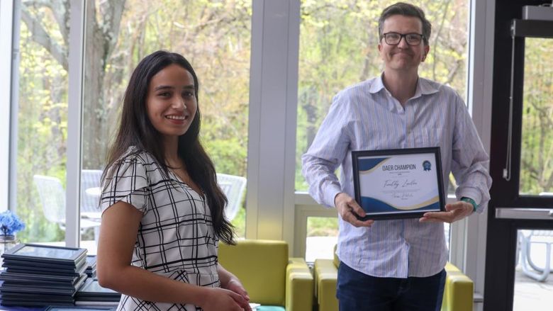 Two people stand with a framed certificate 