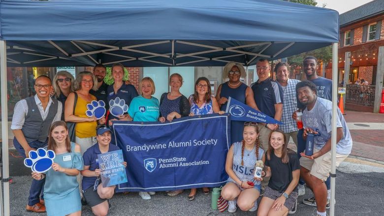 group of people at Dining Under the Stars holding Brandywine Alumni Society banner
