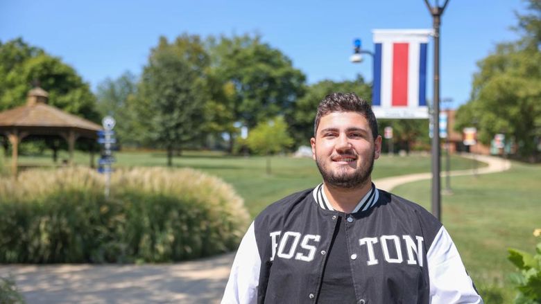 A male student stands on a campus sidewalk at Penn State Brandywine.