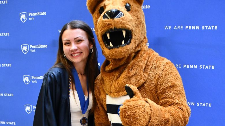 Female student standing next to the Nittany Lion mascot.