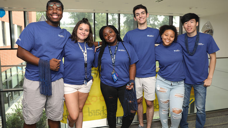 Student volunteers with matching t-shirts posing for a photo in Penn State Brandywine's Orchard Hall.