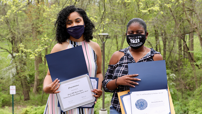 Two female students sharing their award certificates.