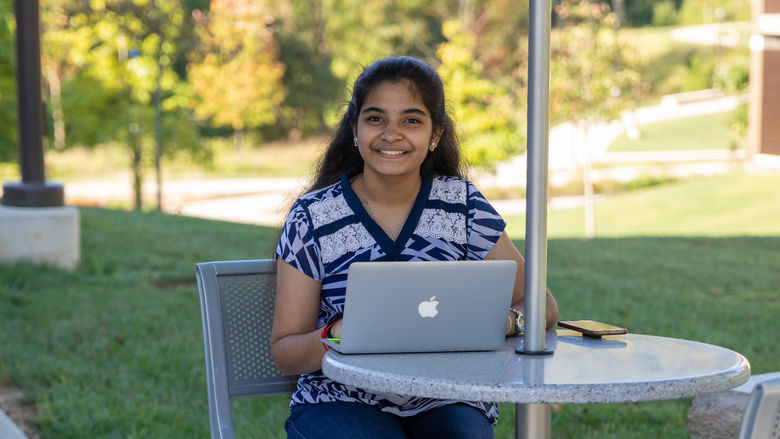 Renusree Bandaru studying outdoors at the Penn State Brandywine campus. 