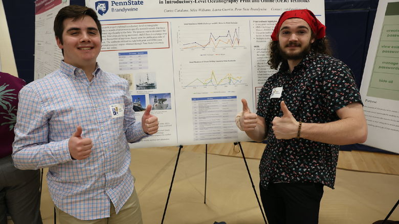 Two men giving thumbs up in front of research poster