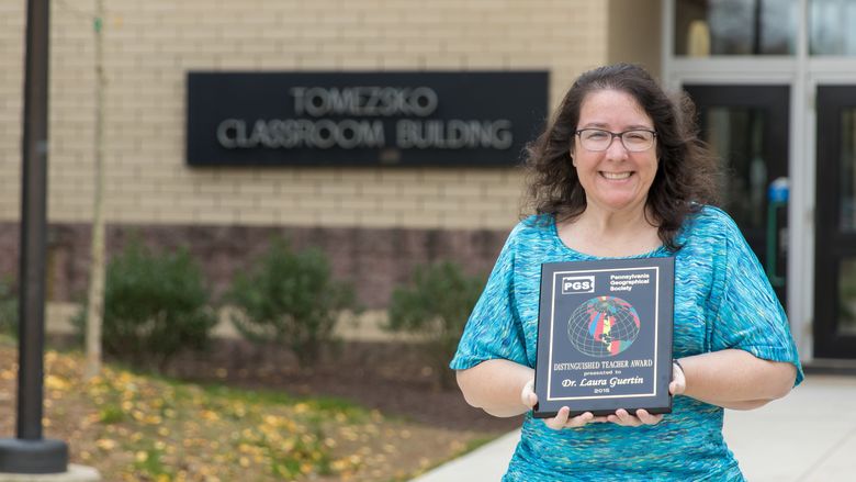 Laura Guertin stands outside with her award plaque.