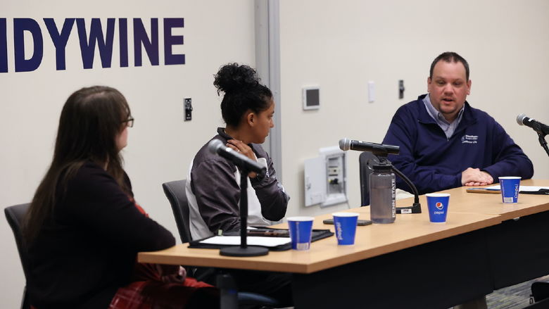 Three staff members sitting at a table with three microphones