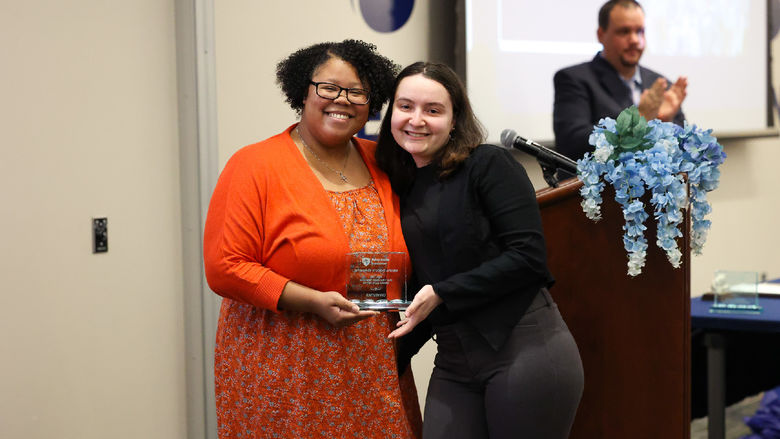 Two women posing holding an award