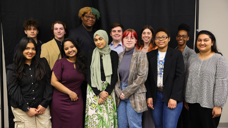 12 students smiling in front of a black backdrop