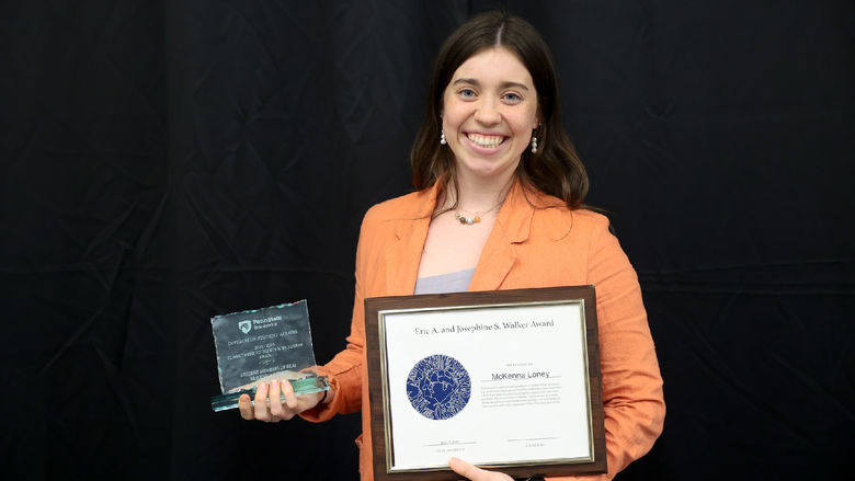 Woman smiling holding two awards