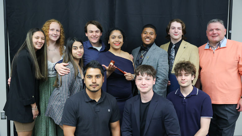 11 people smiling in front of a black backdrop