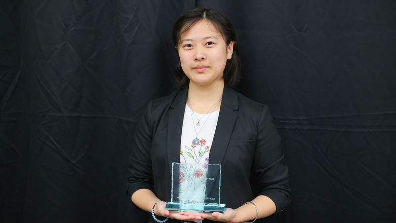 Woman holding an award in front of a black background