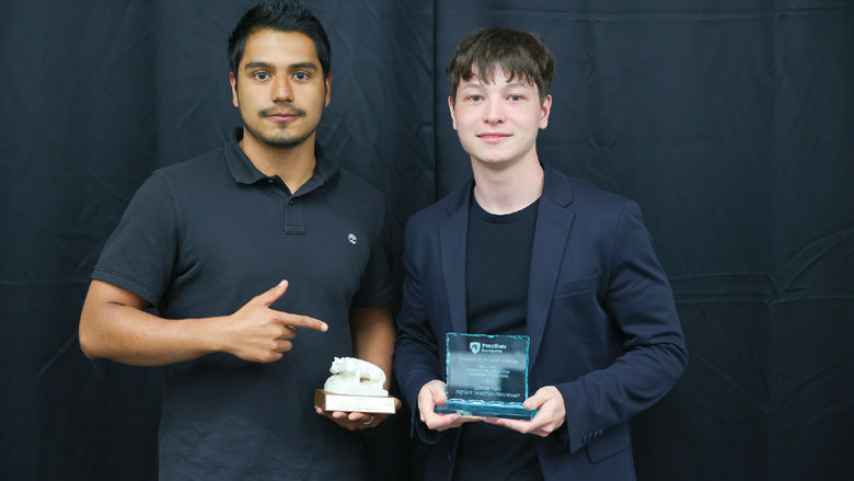 Two men holding awards in front of a black backdrop