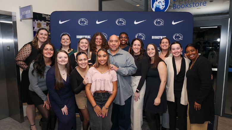 a group of people standing for a photo in front of a penn state backdrop