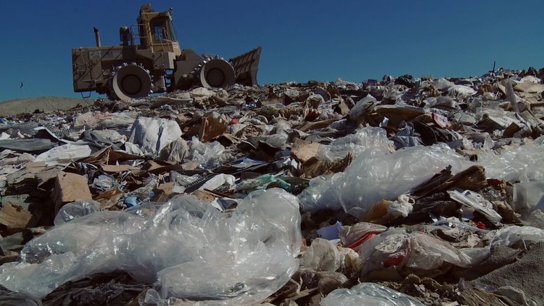 tractor in a landfill, filled with plastic bags
