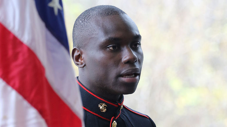 Veteran standing next to American flag.