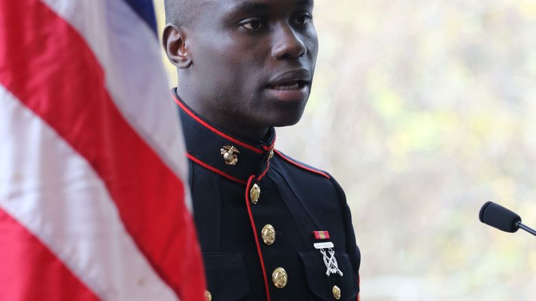 Veteran speaking and standing next to american flag