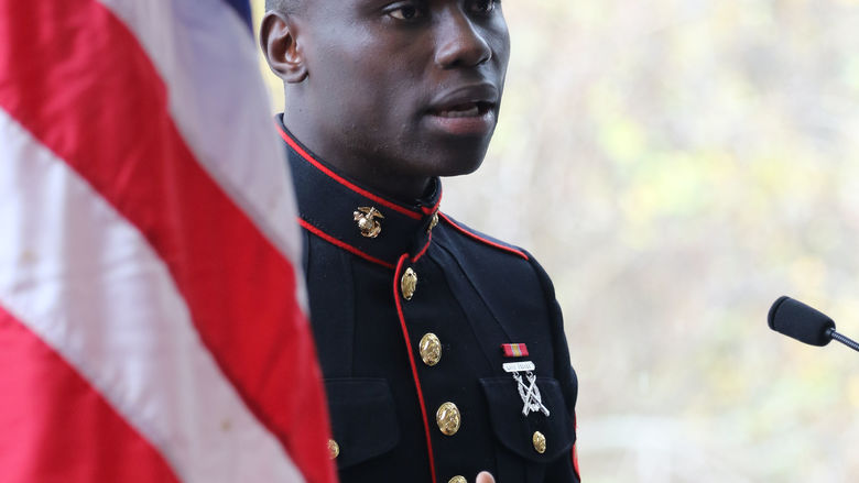 Veteran speaking and standing next to american flag