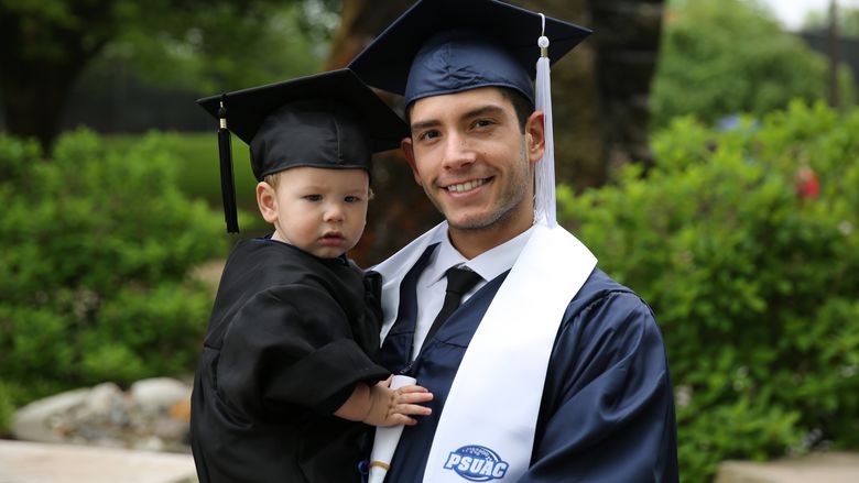 Penn State Brandywine graduate Esteban Munoz holds his son. 