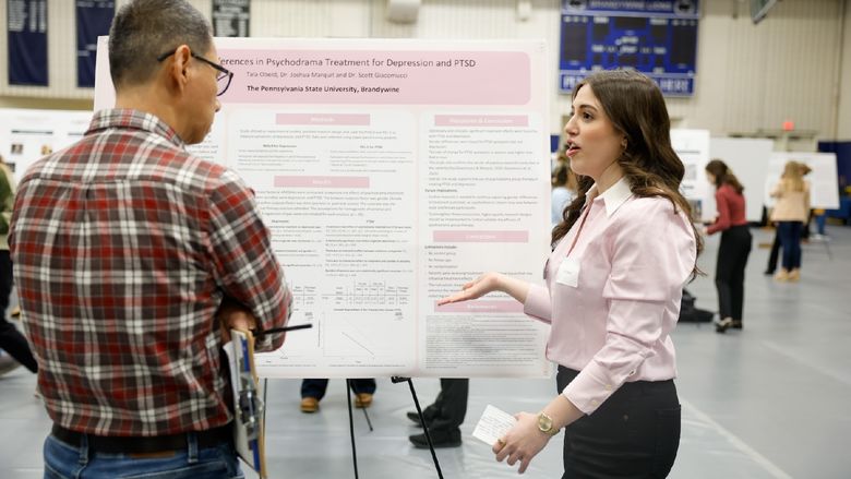 student presenting work on poster board