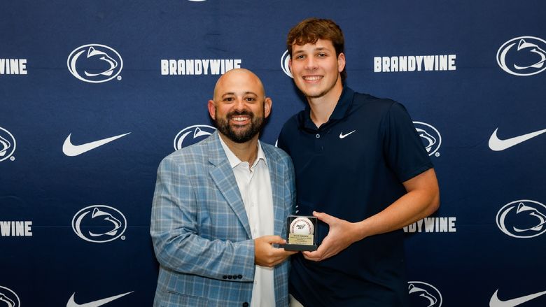 student holding baseball with coach