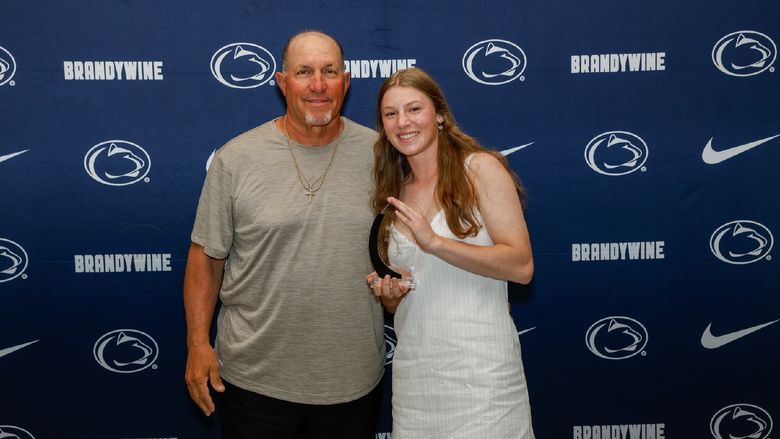 student holding award with coach